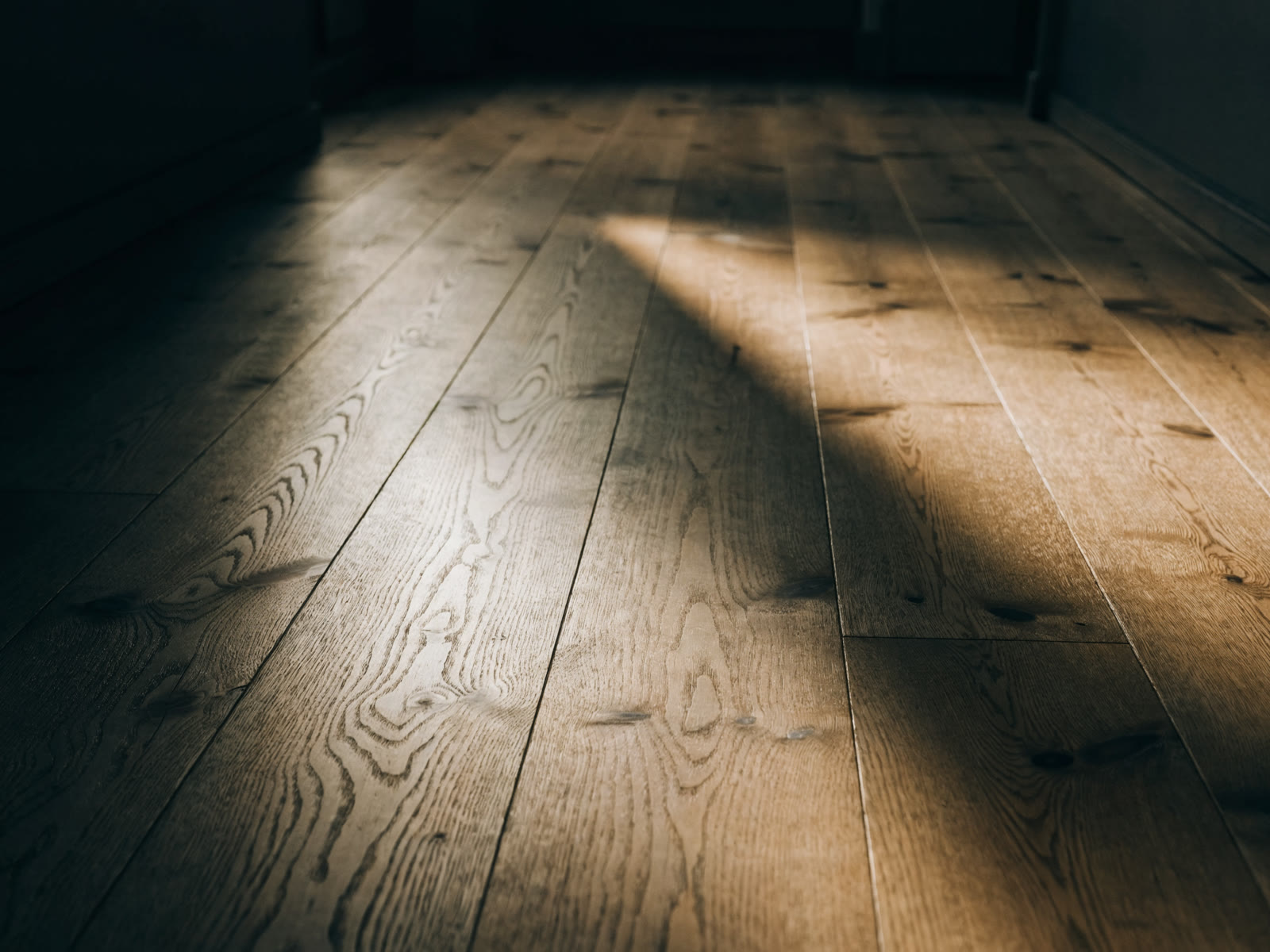 Wide plank hardwood flooring with natural knots in a sunbeam
